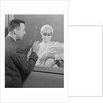 Female nurse holding infant up to father at nursery window by Anonymous