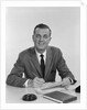 Smiling happy businessman pen in hand signing papers at desk by Anonymous