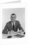Smiling happy businessman pen in hand signing papers at desk by Anonymous