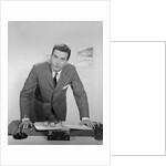 Businessman leaning over desk serious expression looking forward by Anonymous