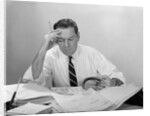 Businessman desk full papers hand to forehead serious expression by Anonymous
