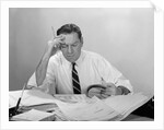 Businessman desk full papers hand to forehead serious expression by Anonymous