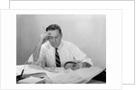 Businessman desk full papers hand to forehead serious expression by Anonymous