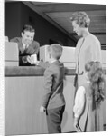 Mother two children boy handing banking deposit to male bank teller by Anonymous