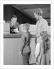 Mother two children boy handing banking deposit to male bank teller by Anonymous
