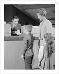 Mother two children boy handing banking deposit to male bank teller by Anonymous