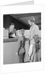Mother two children boy handing banking deposit to male bank teller by Anonymous