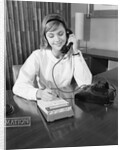 Secretary receptionist talking on telephone writing into desk calendar by Anonymous