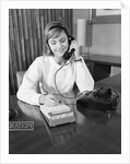 Secretary receptionist talking on telephone writing into desk calendar by Anonymous