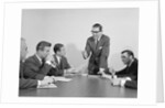 5 executive businessmen meeting at conference table one man standing by Anonymous