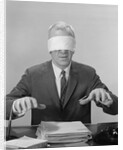 Business man hands hovering over desk wearing blindfold by Anonymous