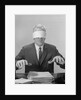 Business man hands hovering over desk wearing blindfold by Anonymous