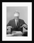 Business man hands hovering over desk wearing blindfold by Anonymous
