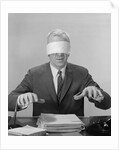 Business man hands hovering over desk wearing blindfold by Anonymous
