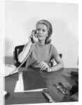 Blond businesswoman talking on telephone sitting at desk by Anonymous