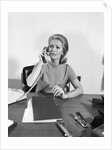 Blond businesswoman talking on telephone sitting at desk by Anonymous