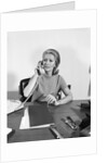 Blond businesswoman talking on telephone sitting at desk by Anonymous