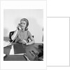 Blond businesswoman talking on telephone sitting at desk by Anonymous