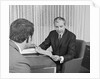 Man from behind meeting at desk of older businessman by Anonymous