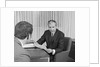 Man from behind meeting at desk of older businessman by Anonymous