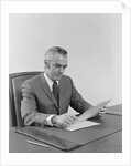 Businessman executive middle aged sitting at desk reading papers by Anonymous