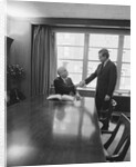 Two men one seated shaking hands long wooden conference table by Anonymous