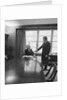 Two men one seated shaking hands long wooden conference table by Anonymous
