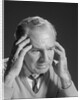 Older man with hands holding head temples by Anonymous