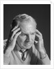 Older man with hands holding head temples by Anonymous