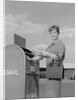 Smiling woman dropping letters in postal mail box by Anonymous