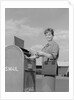 Smiling woman dropping letters in postal mail box by Anonymous