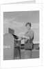 Smiling woman dropping letters in postal mail box by Anonymous