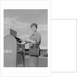 Smiling woman dropping letters in postal mail box by Anonymous