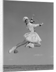 Woman majorette wearing band uniform holding baton jumping into the air by Anonymous