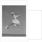 Woman majorette wearing band uniform holding baton jumping into the air by Anonymous