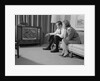 Couple man woman sitting on couch watching television by Anonymous