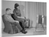 Couple man woman sitting chair watching portable television by Anonymous