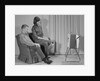 Couple man woman sitting chair watching portable television by Anonymous