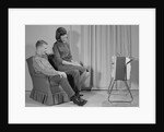 Couple man woman sitting chair watching portable television by Anonymous