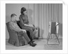 Couple man woman sitting chair watching portable television by Anonymous