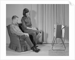Couple man woman sitting chair watching portable television by Anonymous