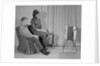 Couple man woman sitting chair watching portable television by Anonymous