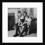 Man father sitting in chair with three children reading book by Anonymous