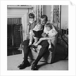 Man father sitting in chair with three children reading book by Anonymous