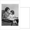 Mother & daughter smiling sitting in chair reading book by Anonymous