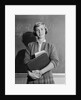Teenage girl holding school books standing in front of blackboard by Anonymous