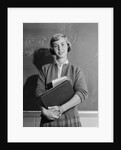 Teenage girl holding school books standing in front of blackboard by Anonymous