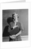 Teenage girl holding school books standing in front of blackboard by Anonymous