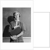 Teenage girl holding school books standing in front of blackboard by Anonymous