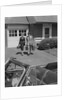 Couple carrying luggage walking towards convertible car in driveway by Anonymous